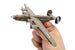 Hand holding a b-24 bomber model airplane with visible branding on a white background