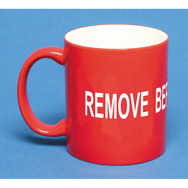 A red ceramic coffee mug with the text 'REMOVE BEFORE FLIGHT' in white capital letters.