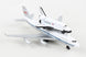 A white and black scale model of the United States Space Shuttle attached to a B-727 passenger jet, with NASA branding visible on the tail fin.