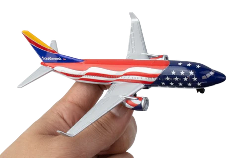 Model airplane with American flag design held by a hand on a white background
